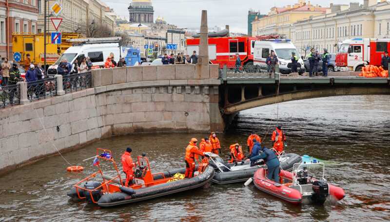 Жители Петербурга несут цветы к месту падения автобуса с моста